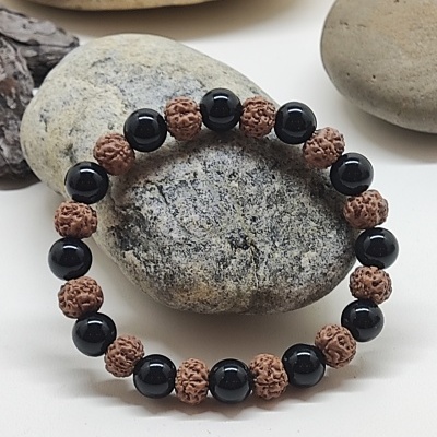 Pulseira com contas negras e castanhas sobre pedras cinzentas