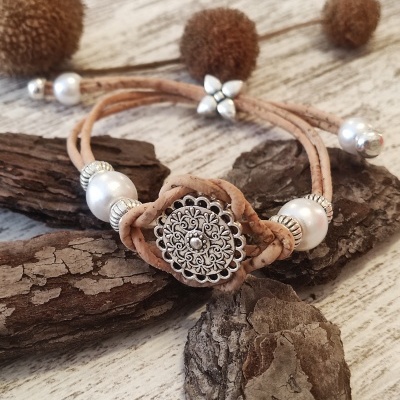 Pulseira bege com contas prateadas e pérolas sobre madeira clara e rústica