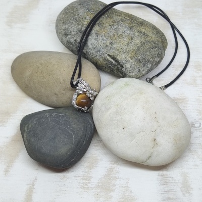 Colar com pedra castanha sobre pedras lisas de várias cores