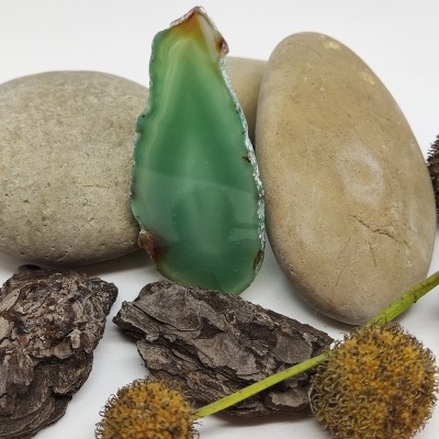 Pedra semipreciosa verde com pedras, cascas e flores secas