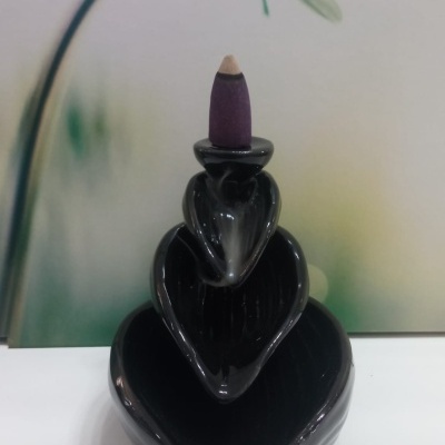 Suporte de incenso preto com cone de incenso roxo em fundo com flor branca