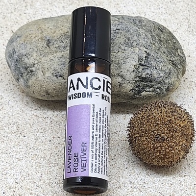 Frasco de óleo essencial roll-on com pedra e semente na superfície clara