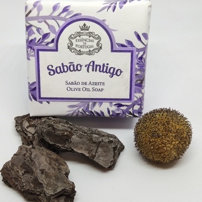 Sabão Antigo em embalagem branca com detalhes roxos e elementos naturais secos em fundo branco