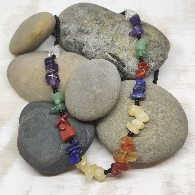 Colar de pedras coloridas irregulares sobre pedras lisas cinzentas
