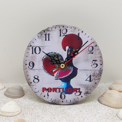 Relógio redondo com imagem de um galo e texto portugal, sobre areia com conchas