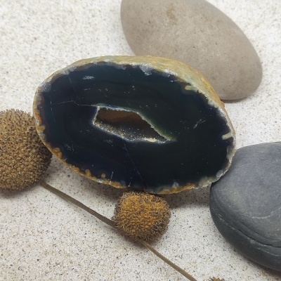 Seixos decorativos com geodo e ramos secos sobre superfície clara