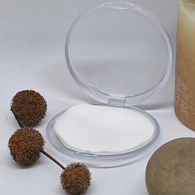 Compacto transparente com almofada branca, ramos secos, vela e pedra