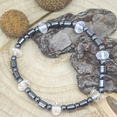 Pulseira com contas pretas e corações translúcidos sobre madeira rústica