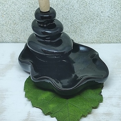 Incensário cerâmica preta com cone de incenso sobre folha verde