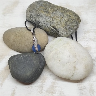 Quatro pedras de cores diferentes, uma com pendente metálico e fio preto.