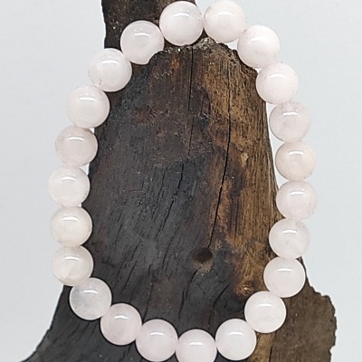 Pulseira de contas de pedra rosa clara sobre madeira castanha rugosa