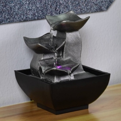 Fonte decorativa metálica com iluminação roxa, base preta quadrada