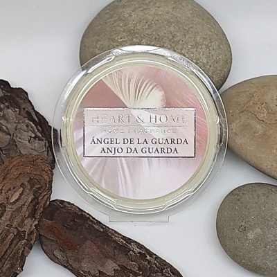 Vela perfumada Heart & Home com rótulo em rosa e branco rodeada por pedras e casca de árvore