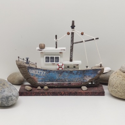 Modelo decorativo de barco de madeira azul e branco com detalhes e pedras ao redor