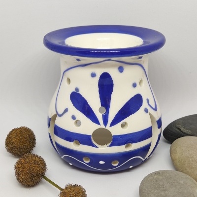 Queimador de cerâmica branco e azul com padrão floral, pedras cinzentas e vagens secas