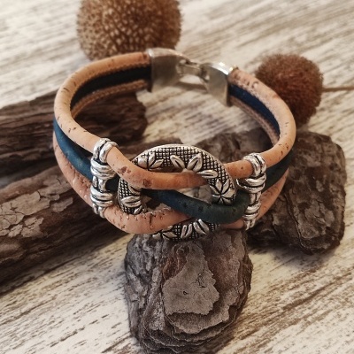 Pulseira de cortiça natural bege e azul com fecho prateado e detalhes florais sobre casca e madeira