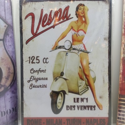 Placa metálica vintage com mulher em fato de banho em cima de mota Vespa e texto em francês