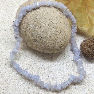 Colar de pedras azuis claras sobre pedra com folha seca a fundo