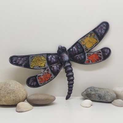 Decoração de parede em forma de libélula com pedras e conchas ao redor