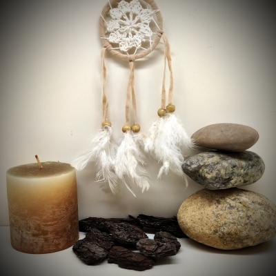 Decoração com filtro dos sonhos, vela, casca e pedras empilhadas