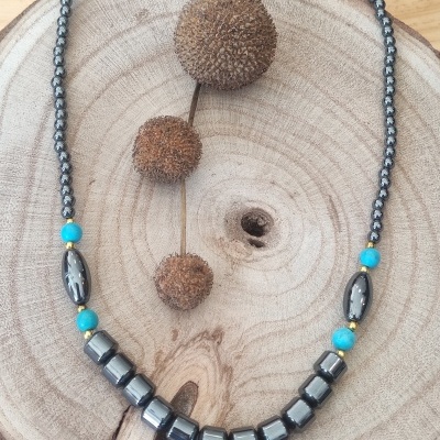 Colar com contas negras e contas azuis turquesa sobre base de madeira clara