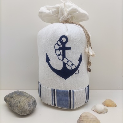 Saco branco com âncora azul e riscas azuis, pedra e conchas