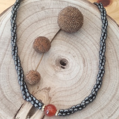 Colar preto e branco com conta vermelha sobre madeira e bolas decorativas