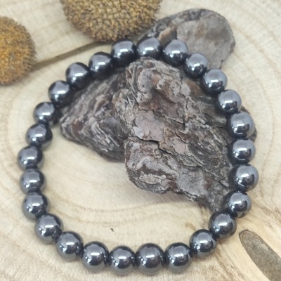 Pulseira de contas metálicas prateadas sobre suporte de madeira clara