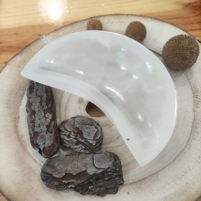 Prato branco meia-lua sobre base de madeira com cascas e bolas secas