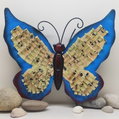 Escultura metálica de borboleta azul e amarela com pedras ao redor