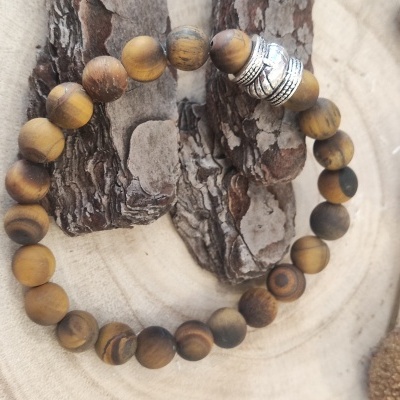 pulseira de contas de madeira castanha com detalhe metálico prateado sobre madeira clara