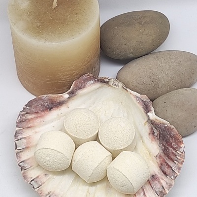 Vela bege, pedras cinzentas e concha com bolas brancas sobre fundo branco