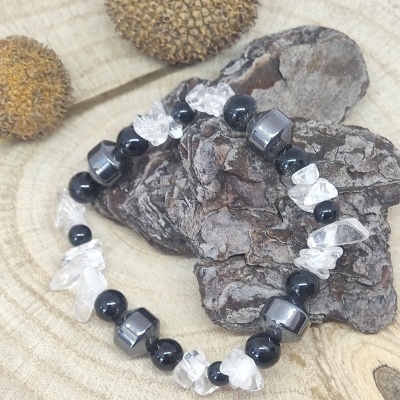 Pulseira de pedras pretas, transparentes e cinzentas sobre casca de árvore