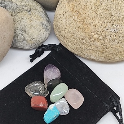 Pedras polidas coloridas sobre saco preto com pedras neutras no fundo