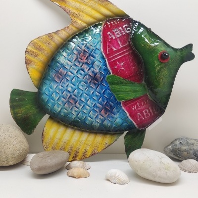 Peixe decorativo metálico colorido com pedras e conchas ao redor