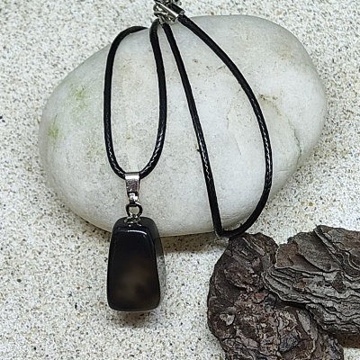 Colar com pendente de pedra preta sobre pedra branca e areia
