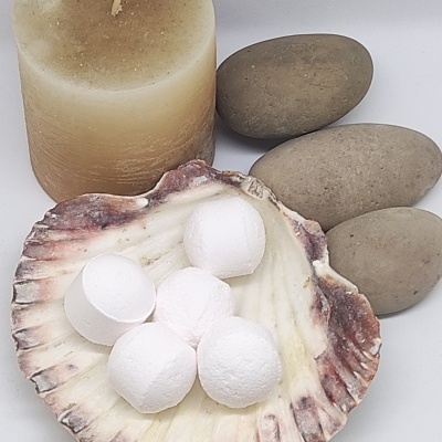 Vela beige cilíndrica, pedras cinzentas lisas, concha com bolas brancas