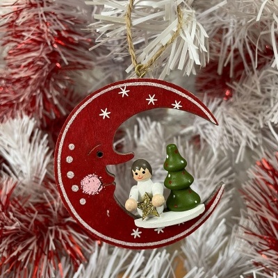 Enfeite de Natal lua vermelha, anjinho e árvore verde pendurado em árvore branca com detalhes vermelhos