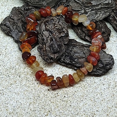 Pulseira de pedras naturais castanhas sobre casca de árvore