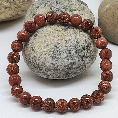 Pulseira de contas castanhas brilhantes sobre pedras naturais cinzentas e bege