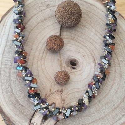 Colar de contas coloridas sobre base de madeira redonda com frutos secos