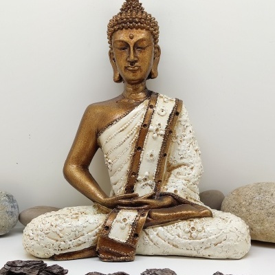 Estátua de Buda dourada e branca em meditação com pedras e madeira