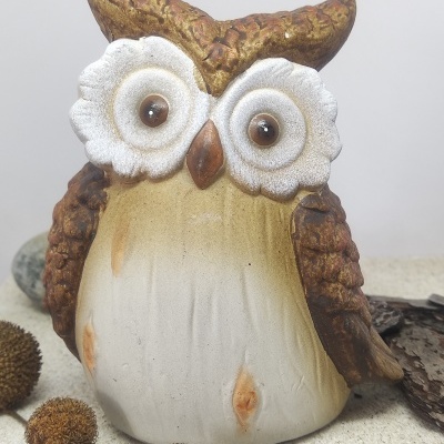 Figura decorativa de coruja em cerâmica com olhos grandes e cores castanho, branco e bege