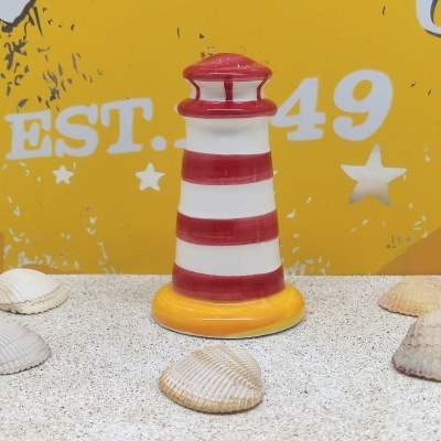 Miniatura decorativa de farol listrado vermelho e branco com base amarela e conchas ao redor