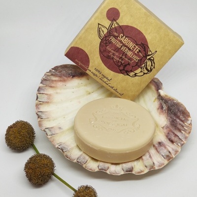 Sabonete redondo bege numa concha com embalagem de papel castanho e flores secas