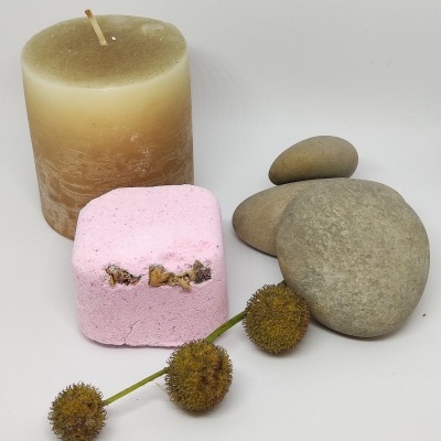 vela creme e marrom, cubo rosa, pedras cinza e ramo com sementes castanhas