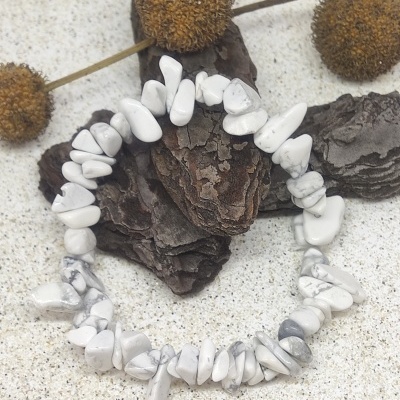 Pulseira elástica com pedras howlite brancas e cinzentas sobre casca de árvore e flores secas
