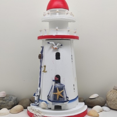 Fanal decorativo em madeira branca e vermelha com detalhes azul, estrela-do-mar e gaivota entre conchas e pedras