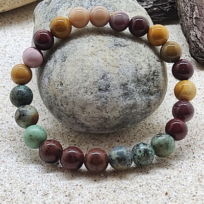 Bracelete de esferas coloridas polidas sobre pedras e cascas