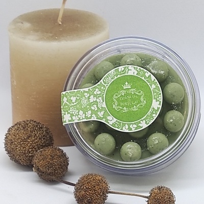 Vela bege, caixa com bolas verdes decorativas e galho de frutos secos secos